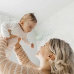 Blond woman lifting son at home